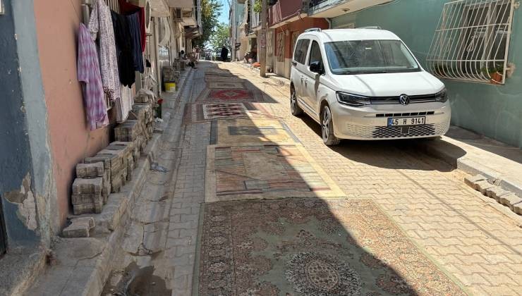 Mahalleli tozdan korunmak için onarılmayan yollara halı serdi